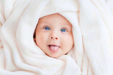 Portrait of a beautiful baby in a white towelの写真素材