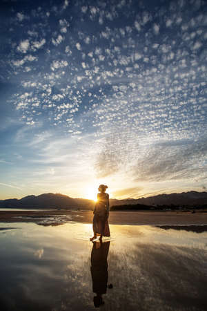 Beautiful woman dancing by the sea at sunsetの写真素材