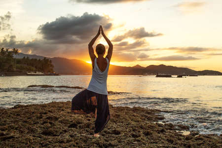 Woman doing yoga by the seaの写真素材