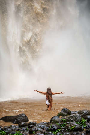 Beautiful woman near a waterfall in Baliの写真素材