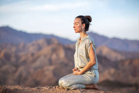 Woman practicing yoga in the mountains in the desertの写真素材
