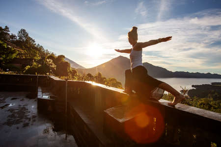 Woman doing yoga at dawn near a volcano on the island of Baliの写真素材