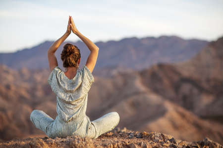 Woman practicing yoga in the mountains in the desertの写真素材