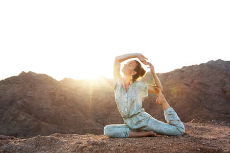 Woman practicing yoga in the mountains in the desertの写真素材