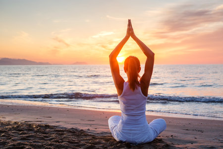 Beautiful woman doing yoga by the seaの写真素材