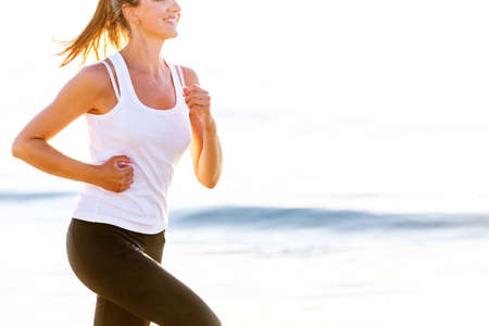 Beautiful woman running by the seaの写真素材