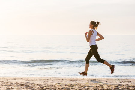 Beautiful woman running by the seaの写真素材