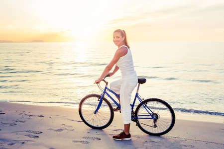 Beautiful woman rides a bicycle by the seaの写真素材