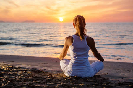 Beautiful woman doing yoga by the seaの写真素材