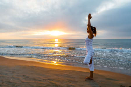 Beautiful woman doing yoga by the seaの写真素材