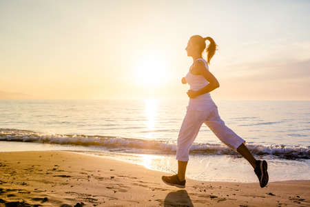 Beautiful woman running by the seaの写真素材