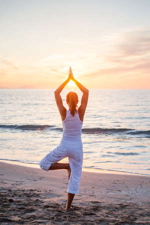 Beautiful woman doing yoga by the seaの写真素材