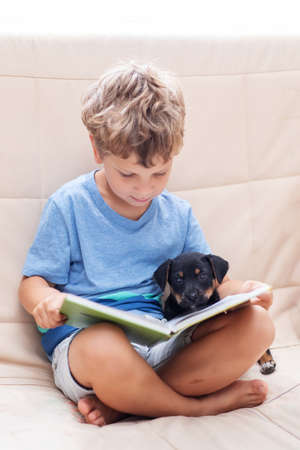 A boy with a little dog is reading a bookの写真素材
