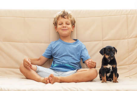 A boy with a little dog doing yogaの写真素材