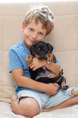 A boy with a little dog playing at homeの写真素材