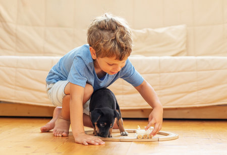 A boy with a little dog is playing in the nurseryの写真素材