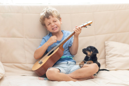 A boy with a small dog playing the ukuleleの写真素材