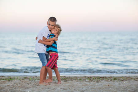 two brothers hugging by the seaの写真素材