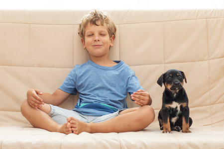 A boy with a little dog doing yogaの写真素材