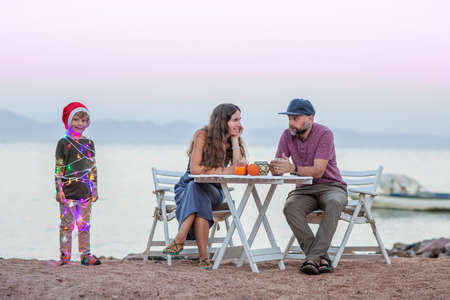 Funny photo about Christmas: parents sitting at the table and the child in the form of a Christmas tree.の写真素材
