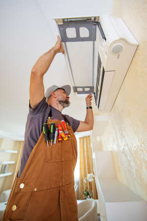 an electrician repairs a home air conditionerの写真素材