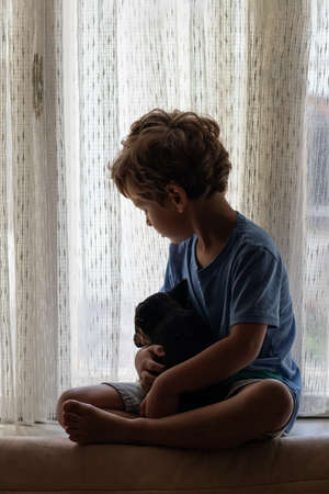 A boy with a little dog playing at homeの写真素材