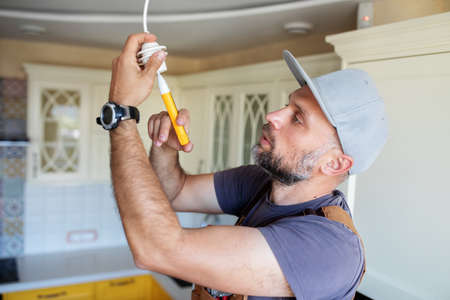 electrician screws a lamp at home in the kitchenの写真素材