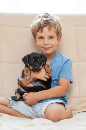A boy with a little dog playing at homeの写真素材
