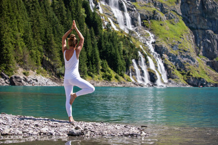 A woman practices yoga in the mountains in Switzerland on Lake Oeschinenseeの写真素材