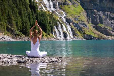 A woman practices yoga in the mountains in Switzerland on Lake Oeschinenseeの写真素材
