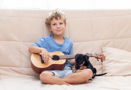 A boy with a small dog playing the ukuleleの写真素材