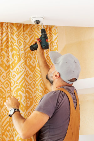 An electrician installs a surveillance camera at homeの写真素材