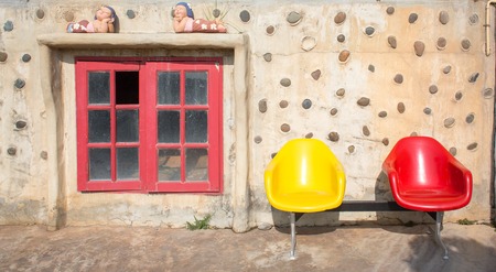 vintage old wall with red window and chairの写真素材