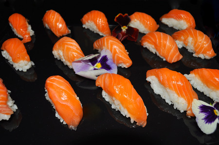 Salmon Nigiri with flowers on black background の写真素材