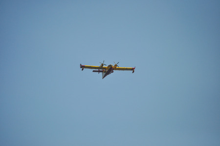 firefighting seaplane flying low yellow and red