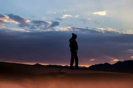 standing female figure with sunset background