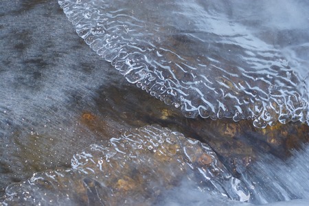 Ice plate and water flow. Winter river flow with transparent ice bubblesの写真素材