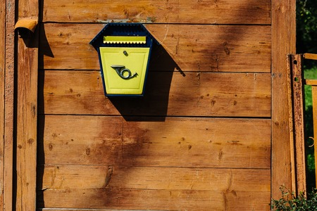 Yellow metal mailbox on a wooden wallの写真素材