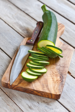 Sliced zucchini on wooden plank with knife. Selective focus.の写真素材