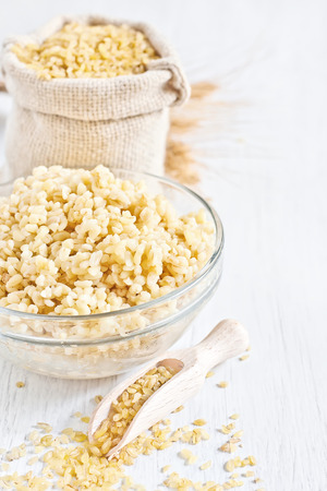 Raw and cooked cracked durum wheat or bulgur in bag. Popular ingredient in Middle Eastern cuisine. Copy space background.の写真素材