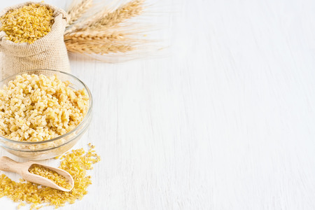 Raw and cooked cracked durum wheat or bulgur in bag. Popular ingredient in Middle Eastern cuisine. Copy space background.の写真素材