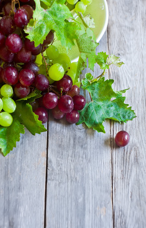 Ripe green and red grape in ceramic bowlの写真素材