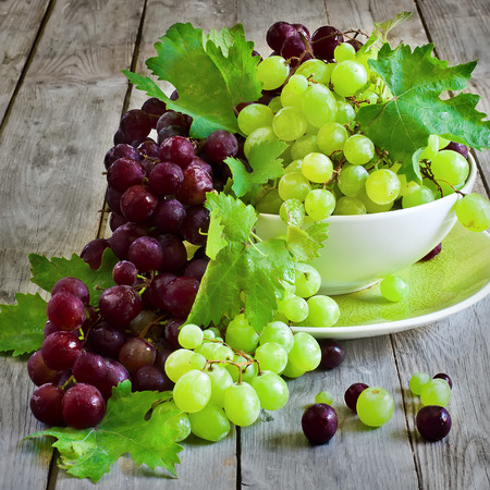 Ripe green and red grape in ceramic bowlの写真素材