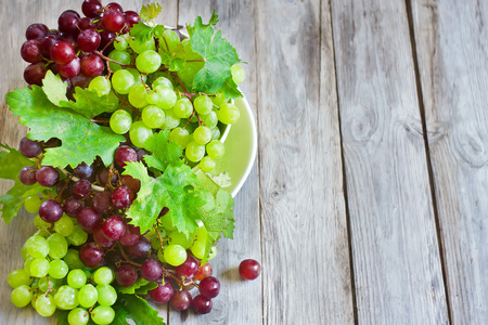 Ripe green and red grape in ceramic bowlの写真素材