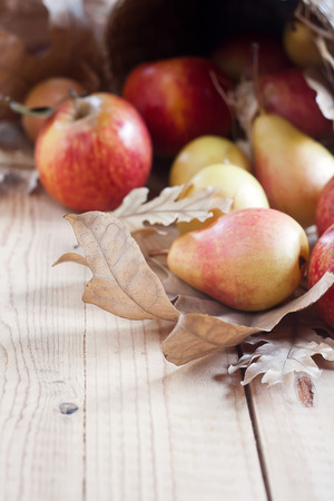 Ripe pears and apples with dry fall leaves on wooden background. Selective focus. Copyspace background.の写真素材