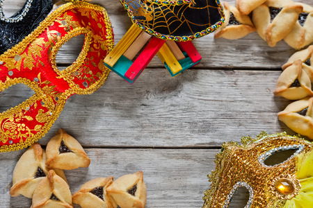Hamantaschen cookies or Haman's ears, noisemaker and carnival masks for Purim celebration (jewish holiday). Copy space background.の写真素材