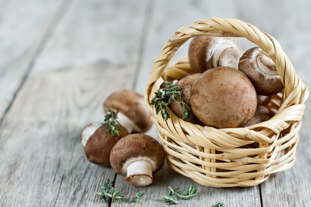 Fresh raw portabello mushrooms in wicker basket on dark wooden backgroundの写真素材