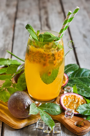 Homemade lemonade with passionfruit, mint leaves and ice cubes on old wooden backgroundの写真素材