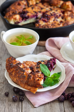 Black currant pie with cups of tea on old wooden backgroundの写真素材