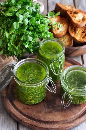Homemade cilantro pesto in jars on wooden backgroundの写真素材